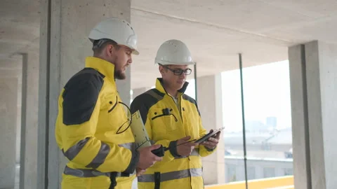 Two Engineer In Helmets With Tablet Device And Big Paper Drawings Discussing Video stock 114538202