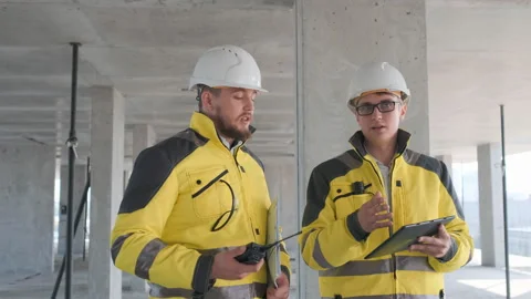 Two Engineer In Helmets With Tablet Device And Big Paper Drawings Discussing Stock Footage 114539375