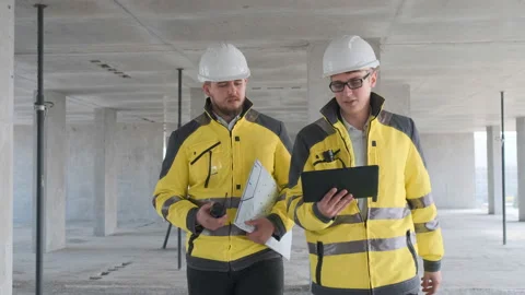 Two Engineer In Helmets With Tablet Device And Big Paper Drawings Discussing Stock Footage 114539653