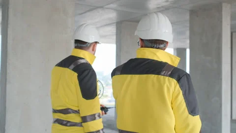 Two Engineer In Helmets With Tablet Device And Big Paper Drawings Discussing Stock Footage 114539749