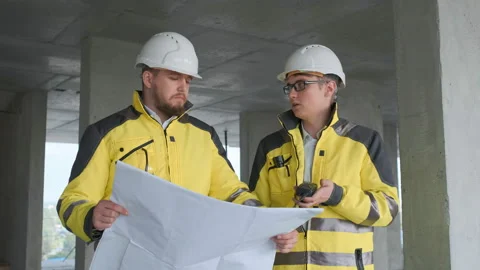 Two Engineer In Helmets With Tablet Device And Big Paper Drawings Discussing Video stock 114540055