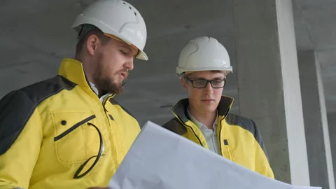 Two Engineer In Helmets With Tablet Device And Big Paper Drawings Discussing Video stock 114540159