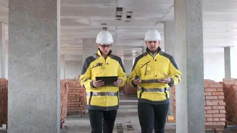 Two Engineer In Helmets With Tablet Device And Big Paper Drawings Discussing Stock Footage 114541117