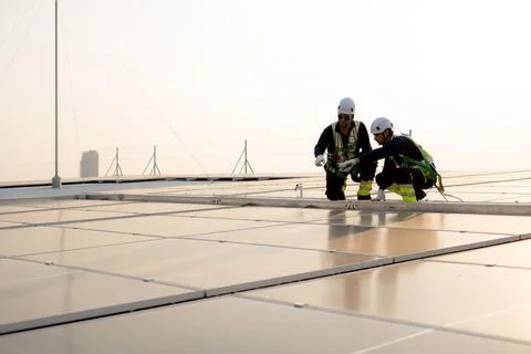 Two engineer inspecting solar panel on roof of building, team man worker or.. Stock Photos