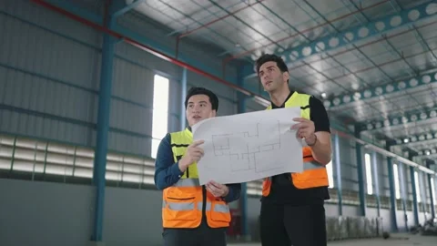 Two engineer male talking, discuss looking at paper work in factory Industrial Video stock 236351057