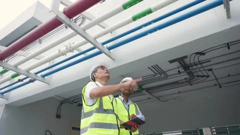 Two engineer men in safety gear are looking at a tablet. They are wearing y.. Stock Footage 280732462