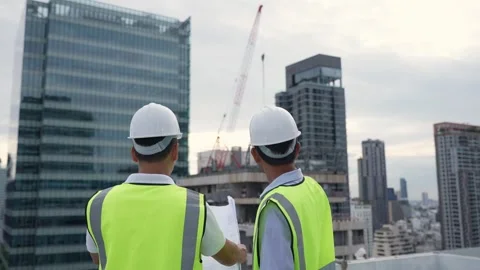 Two engineer men in safety vests are standing on a rooftop of a building. T.. Stock Footage 280732440