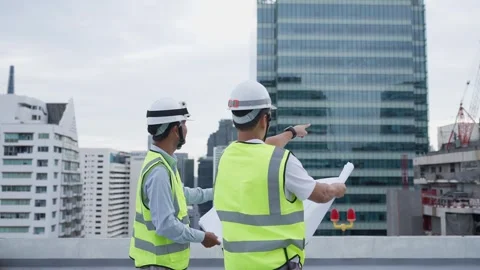 Two engineer men in safety vests are standing working Видео 280732511