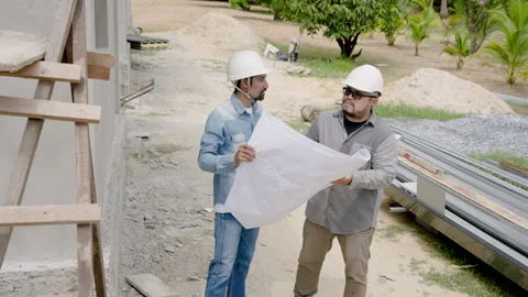 Two engineer men wearing safety helmets for safety while in construction Stock Footage 253085051