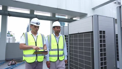 Two engineer men in yellow vests are standing next to a large air condition.. Stock Footage 280732474
