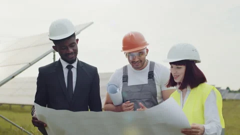 Two engineers and one technician examining drawings of solar farm while standing Video stock 168495205