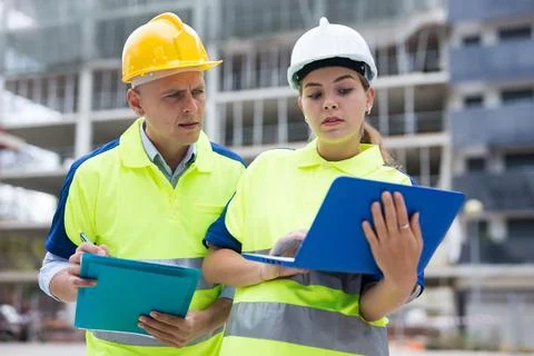 Two engineers are discussing an important project, holding a laptop and an Stock Photos
