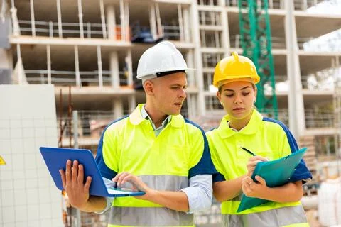 Two engineers are discussing an important project, holding a laptop and an Stock Photos