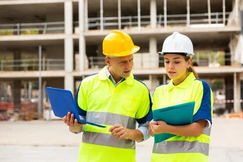 Two engineers are discussing an important project, holding a laptop and an Stock Photos