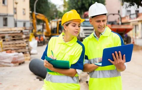 Two engineers are discussing an important project, holding a laptop and an Stock Photos