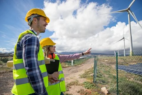 Two engineers are having a conversation while observing wind turbines, rene.. Foto stock