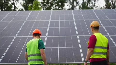 Two engineers are talking and smiling against the background of solar panels. Stock Footage 318591258