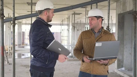 Two engineers browsing laptop and discussing building work. 库存影片 72359224
