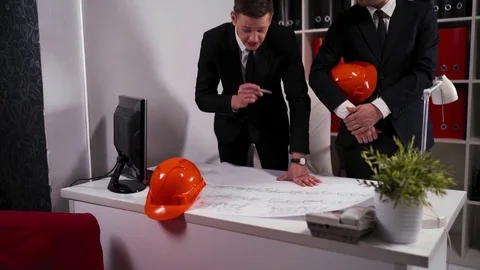 Two engineers businessmen look at architect drawing with helmet Stock Footage 79045852