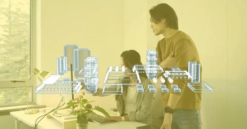 Two engineers collaborating at office workspace with 3D blueprint floating above Stock Photos