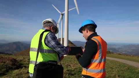 Two engineers collaborating using tablet near wind turbines Stock Footage 294975823