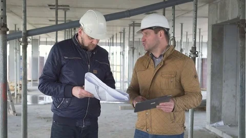Two engineers compare building project with data on tablet. 库存影片 72358799