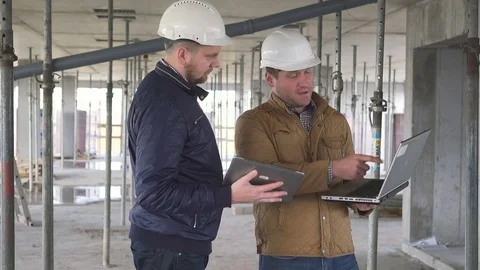 Two engineers compare data on tablet and laptop and arguing about building work. Video stock 72359317