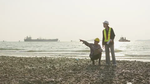 Two engineers conduct an environmental site assessment on a rocky shoreline Stock Footage 335700025
