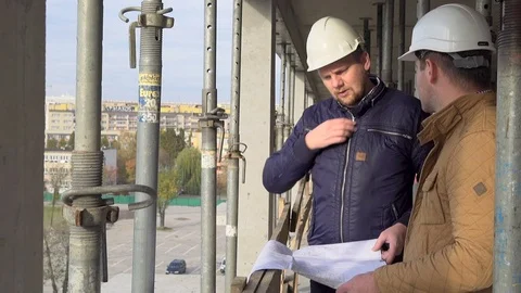 Two engineers consulting building project while one talking by smartphon. 動画素材 72359517