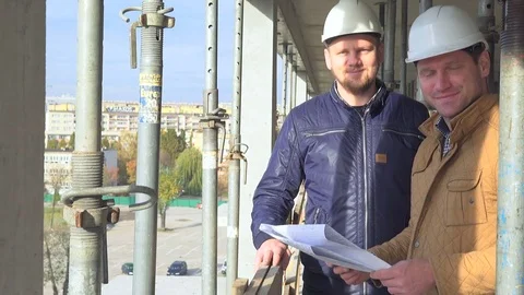 Two engineers consulting building project and smiling to camera. 库存影片 72359913