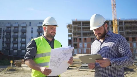 Two engineers consulting  work progress at construction, slider shot. Vídeos de archivo 70785838