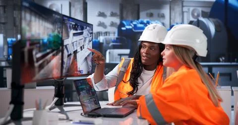 Two Engineers Discuss 3D Pipeline Designs On A Laptop Inside Power Plant. Stock Photos
