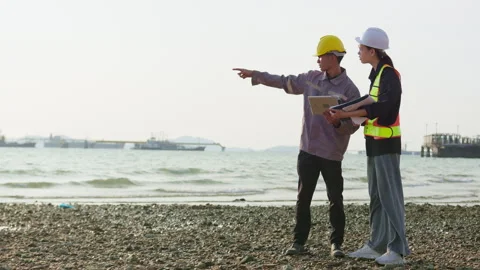 Two engineers discuss a coastal development project on a shoreline Stock Footage 346636089