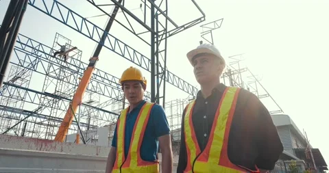 Two engineers discuss plan of building at construction site Stock Footage 156385116