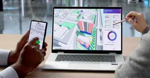 Two Engineers Discuss Site Plans Using Laptop And Smartphone For Mapping, Des Stock Photos