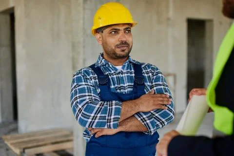 Two engineers discuss work related questions together holding folded blueprint. Stock Photos