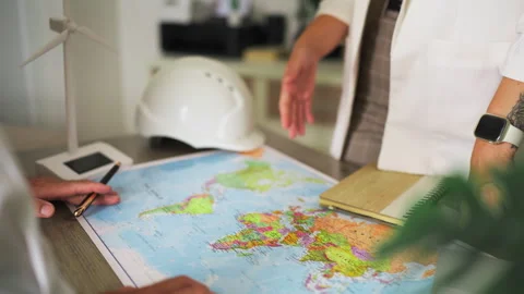 Two engineers discussing global renewable energy strategy and pointing at l.. Stock Footage 346172142