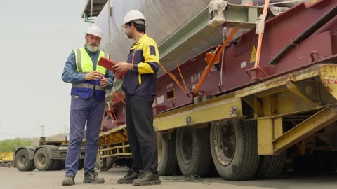 Two engineers in hard hats discuss logistics for transporting oversized heavy Stock Footage 342280689