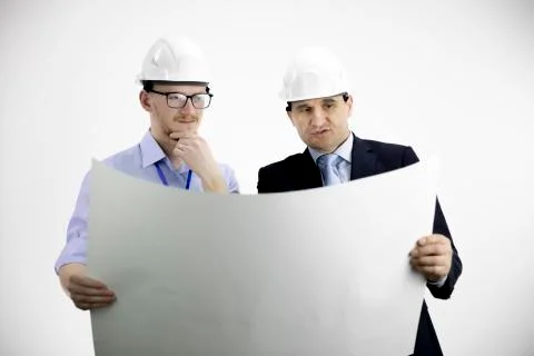 Two engineers in hard hats working, meeting, discussing layout of building Stock Photos