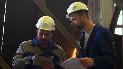 Two engineers in hardhat discussing with tablet and blueprint Stock Photos