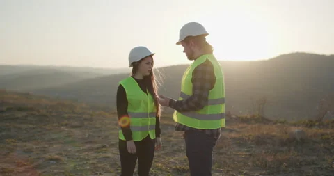 Two engineers in hardhats shaking hands and discussing in front of welding Stock Footage 195250832