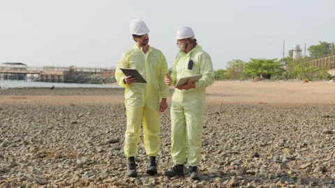 Two engineers in hazmat suits collaborate on a site survey Stock Footage 338294420