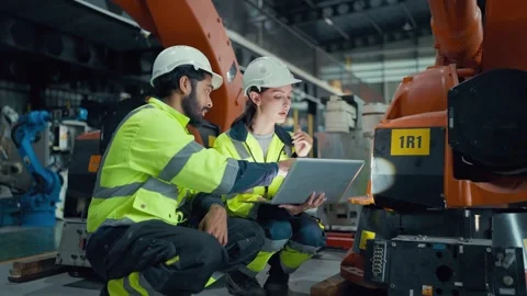 Two engineers inspect robotic equipment in a factory Stock Footage 340982718