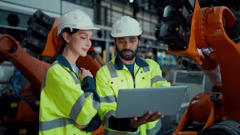 Two engineers inspect robotic machinery in a factory 库存影片 347351858