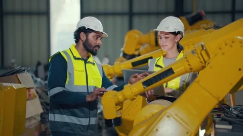 Two engineers inspect yellow robotic arm in factory Video stock 340986822