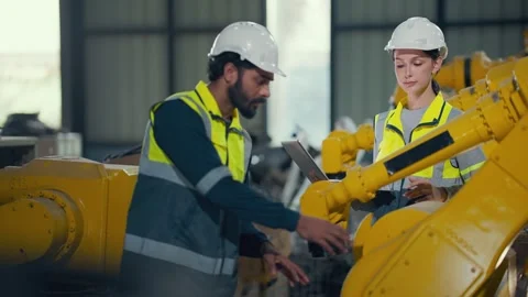 Two engineers inspect yellow robotic arm in factory Video stock 340987319
