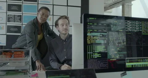 Two Engineers looking at Code on Computer Monitor in Office Stock Footage 240228484