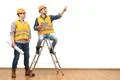 The two engineers near the ladder gesture on the white wall background Photo