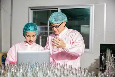 Two engineers oversee quality control checking product bottles on a beverage Stock Photos