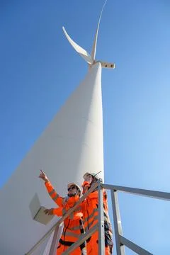 Two engineers in safety uniform inspecting wind turbine Foto stock